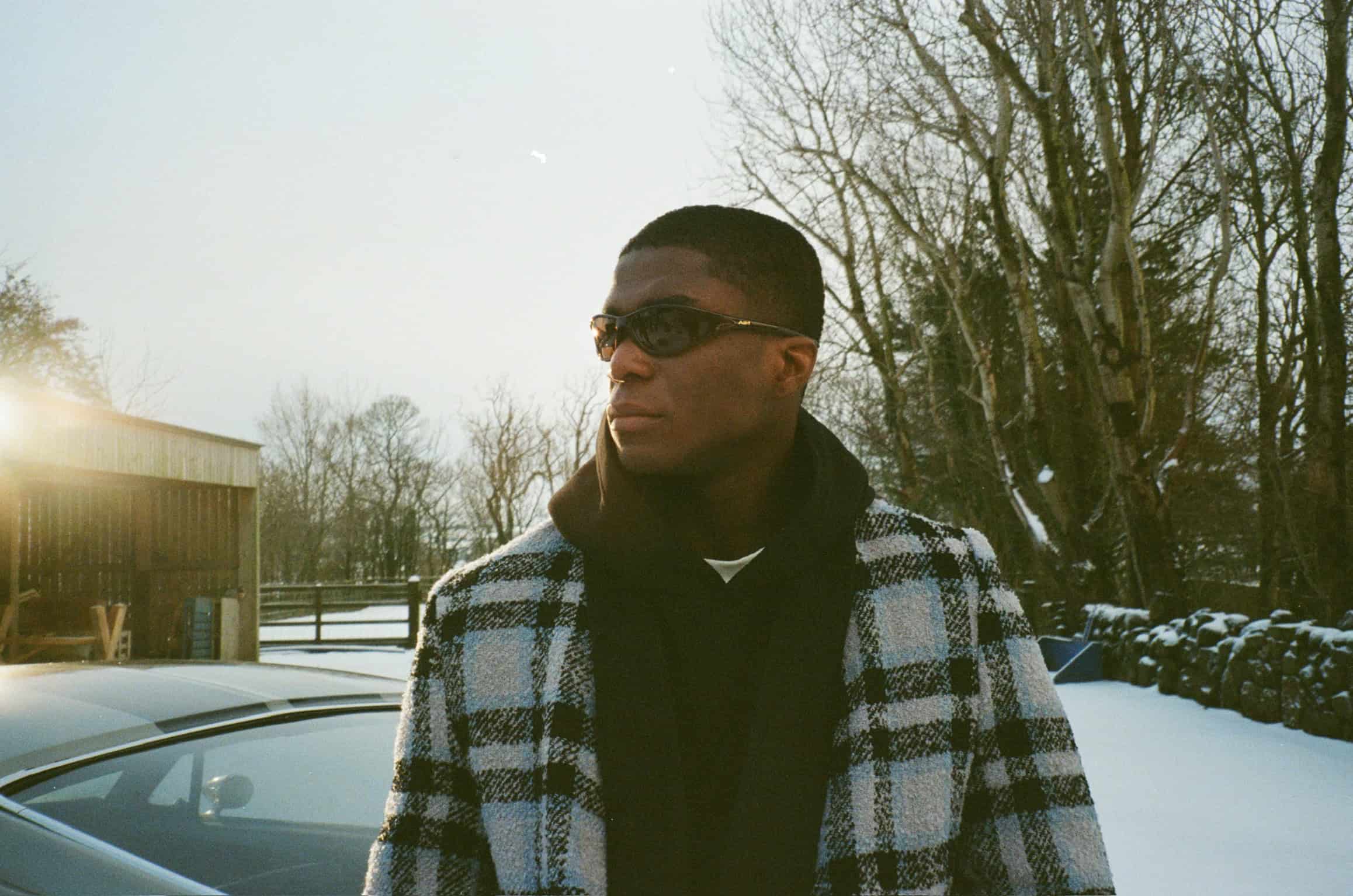 Campaign model Patrick wearing sunglasses and the wool "the harvest coat" paired with "the steal hoodie" from the sixth language's debut "intro collection".