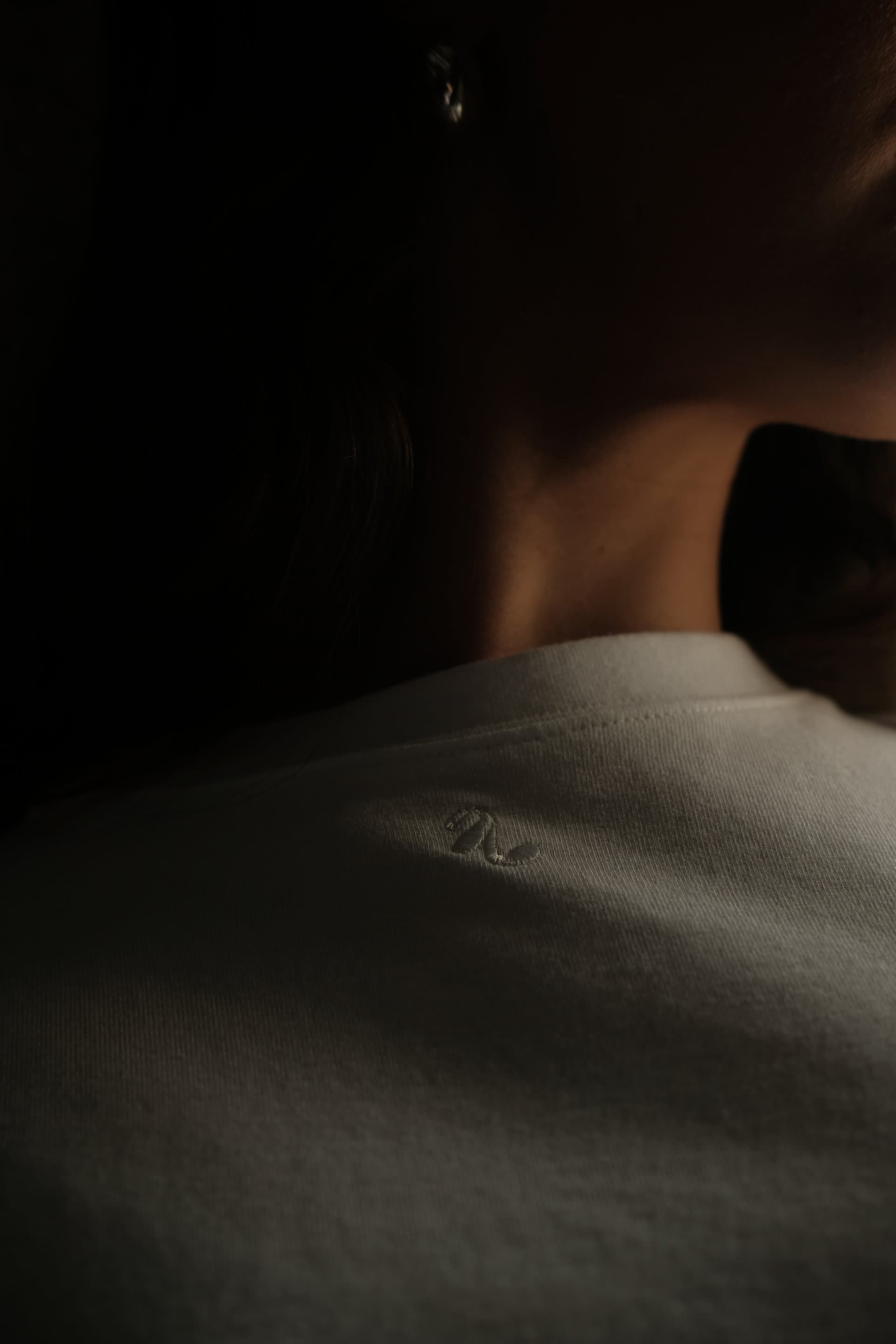 Close up  detail of the neckline of the masterpiece shirt showing off the Sixth Languages brand mark delicately and subtly embroidered. 